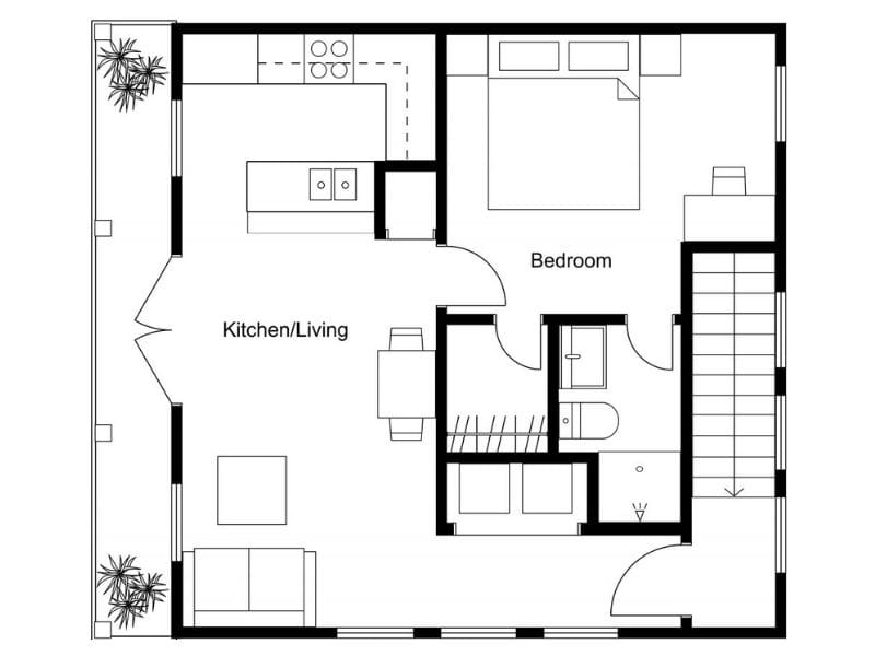 Black-and-white 2D floor plan of a small apartment or home layout. The space includes a combined kitchen and living area with a sofa, dining table, and L-shaped kitchen counter. One bedroom is shown with a double bed and side tables. Adjacent to the bedroom is a bathroom with a bathtub, toilet, and sink. A small room, possibly a storage or utility room, is next to the bathroom. Stairs are positioned on the right side of the plan, and entry is through the lower right door. Potted plants are placed outside the perimeter.