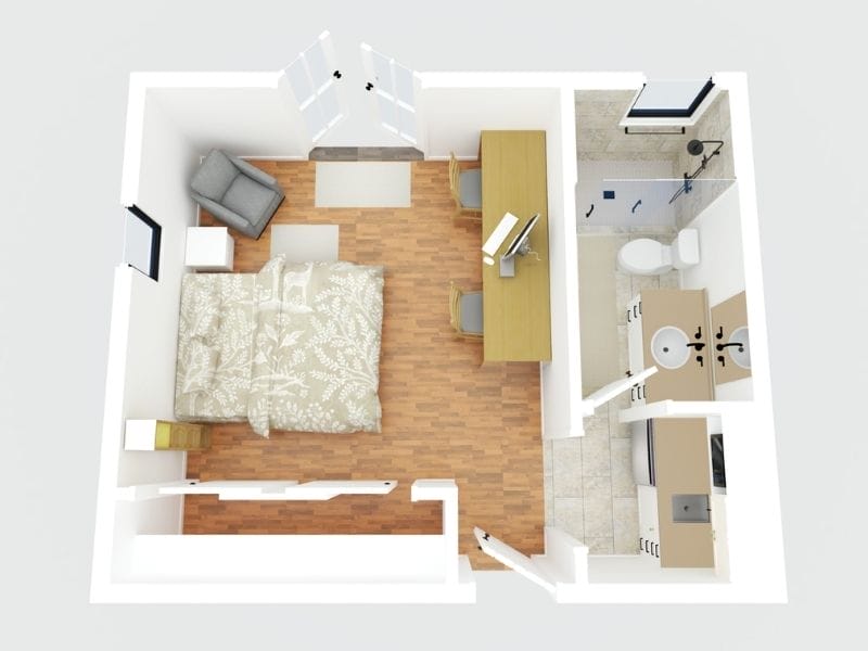 3D floor plan made with CubiCasa. The floor plan shows a hotel room, with a double bed, a shelf and a nightstand next to the bed, a grey chair in the corner of the room and a long table against the opposite wall of the bed with a computer and two chairs. There is a closet on the wall that leads to the hallway outside the room. To the right there is a small kitchen area with a sink, some drawers and a fridge. In the room next to the kitchen area is the bathroom with a sink, toilet and a shower.
