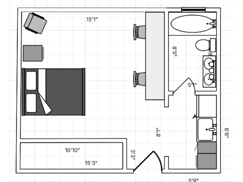2D floor plan made with Lucidchart software. The floor plan is of a hotel room with a bed, safe, chair, a longer table and two chairs, a small kitchen area, and a bathroom with jack-and-jill sinks.