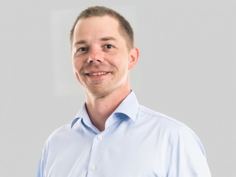 Home builder Tommy Nyborg in a light blue dress shirt posing against a plain light gray background.